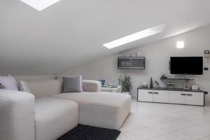 a white living room with a couch and a tv at Mansarda Massimo - Verbania Intra in Verbania