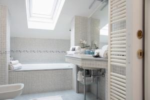 a white bathroom with a tub and a sink at Mansarda Massimo - Verbania Intra in Verbania +17 photos