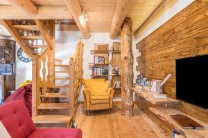 a living room with wooden walls and a staircase and a television at Baita Dani in Primiero
