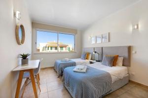 a bedroom with two beds and a table and a window at Lagos Beach Pool Villa in Lagos +18 photos