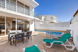 a patio with a table and chairs next to a swimming pool at Lagos Beach Pool Villa in Lagos