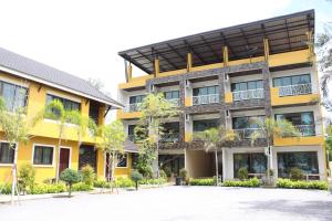 a yellow building with trees in front of it at Yellow House Rayong in Ban Phe