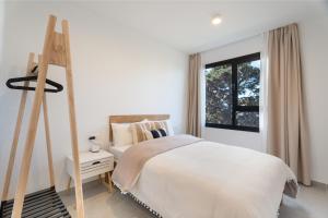 a white bedroom with a bed and a window at Buena - Vista in La Guancha +26 photos