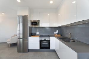 a kitchen with white cabinets and a stainless steel refrigerator at Buena - Vista in La Guancha