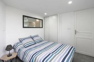 a bedroom with a bed with striped sheets and a mirror at Appartement dans maison atypique in Montrond-les-Bains
