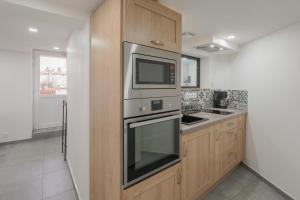 a kitchen with stainless steel appliances and wooden cabinets at Appartement dans maison atypique in Montrond-les-Bains