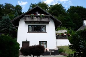 a white house with a balcony with flowers on it at Ferienhaus zum Frankenblick in Sonneberg