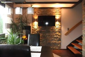 a living room with a stone wall with a tv at Ferienhaus zum Frankenblick in Sonneberg