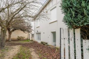 a white building with a fence and trees at Appartement dans maison atypique in Montrond-les-Bains