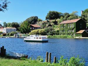 a boat on a river with a building in the background at La tiny house de la Blandinière in Vertou
