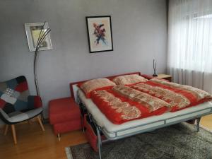 a bedroom with a bed with red blankets and a chair at Ferienwohnung Diepold in Wasserburg