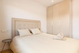 a bedroom with a large white bed and a stool at Blue Coast Apartment in Canet de Mar