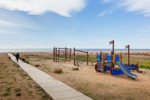 a playground on the beach with a person walking a dog at Blue Coast Apartment in Canet de Mar
