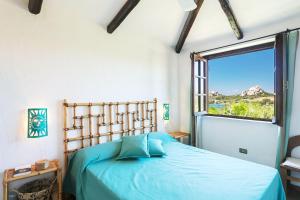 a bedroom with a blue bed with a window at Casa Mucchi Bianchi PC33 in Arzachena