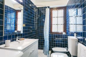 a blue tiled bathroom with a toilet and a sink at Casa Mucchi Bianchi PC33 in Arzachena