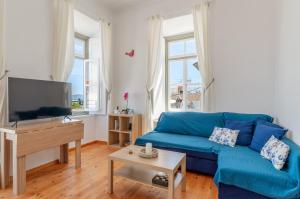 a living room with a blue couch and a flat screen tv at Martha's House in Spetses