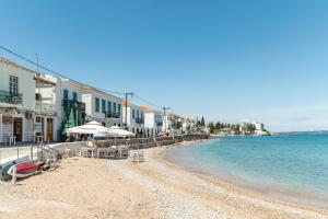 a beach with chairs and umbrellas next to the water at Martha's House in Spetses
