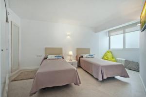 two beds in a white room with windows at Maina 1919 in Pollença