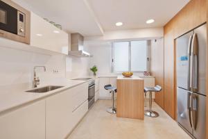 a kitchen with white cabinets and a sink and a refrigerator at Maina 1919 in Pollença