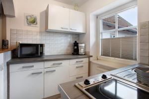 a kitchen with white cabinets and a sink and a microwave at Bäckerhus - Ferienwohnung 3 in Wiek auf Rügen