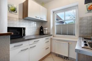 a kitchen with white cabinets and a window at Bäckerhus - Ferienwohnung 3 in Wiek auf Rügen +11 photos