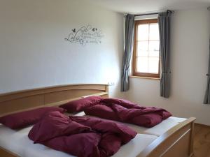 a bed with purple pillows on it with a window at Fischerhof in Höchenschwand