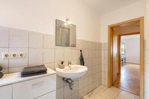 ein weißes Badezimmer mit Waschbecken und Spiegel in der Unterkunft Wohnung Weida in Riesa + 17 Fotos
