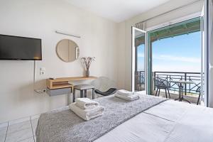 a bedroom with a bed with a desk and a balcony at Sunset Premium Studio 7 in Lefkada +25 photos