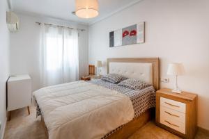 a bedroom with a bed and a dresser with a lamp at Almdna15-atc in Torrevieja