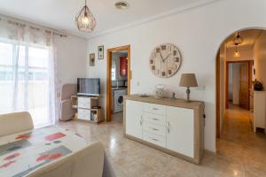 a living room with a table and a clock on the wall at Almdna15-atc in Torrevieja