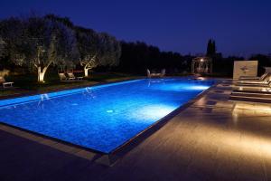 a large swimming pool with blue water at night at Abaye 5 Barolo - Charm Adults Only in Soiano del Lago