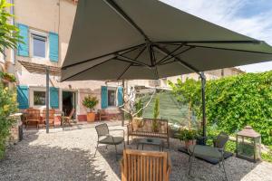 a patio with a large green umbrella and chairs at La maison d'à côté in Carpentras