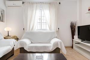 a white living room with a chair and a tv at Vejer 1 - Andalmar in Vejer de la Frontera