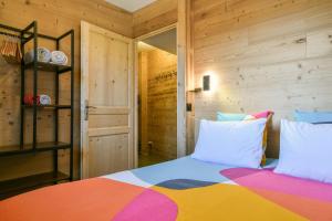 a bedroom with a colorful bed with wooden walls at L’ourson in Les Déserts +16 photos