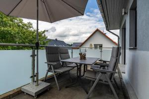a table and chairs on a balcony with an umbrella at Ferienvilla Kapitänshaus in Karlshagen