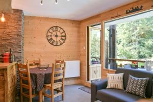 a dining room with a table and a clock on the wall at L’ourson in Les Déserts
