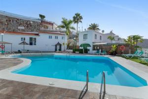 a large blue swimming pool in front of a building at Sunset Apartment in Puerto Rico de Gran Canaria