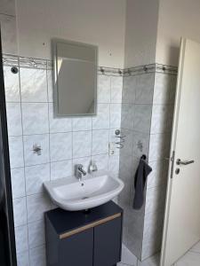 a bathroom with a sink and a shower with a mirror at Ferienwohnung Waldblick Alterkülz in Alterkülz +13 photos