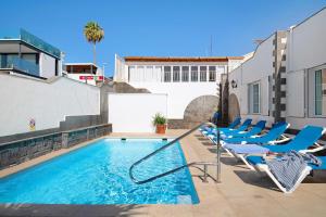 a swimming pool with lounge chairs on a building at Villa Muñoz in Puerto del Carmen