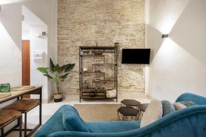 a living room with blue furniture and a brick wall at Bella Encantada in Cádiz