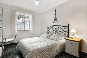 a white bedroom with a bed and a chair at Cal Guerrer in Mogente
