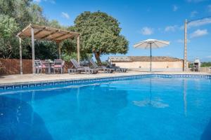 a swimming pool with a table and chairs and an umbrella at Ses Comes de Son Cladera in Manacor