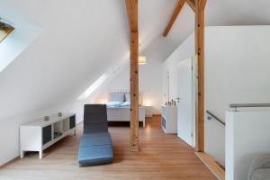 a white attic bedroom with a bed and a blue couch at Ferienwohnung am Hirschfelsen in Bühlertal