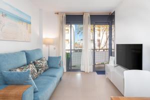 a living room with a blue couch and a tv at Mar i Llum in Platja d'Aro