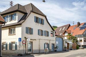 a white building with blue shutters on a street at Ferienwohnung Zur Weinsteige in Ihringen
