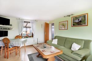 a living room with a green couch and a table at Landferien Schütt in Neuenkirchen