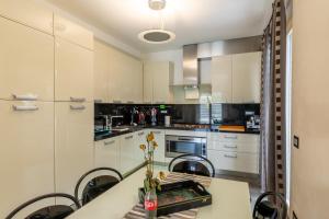 a kitchen with white cabinets and a table with chairs at Relax in Villa - Versilia in Massa