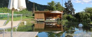 a house with a reflection in the water with an umbrella at Rosengartnerhof Apt Vorberg in Terlano