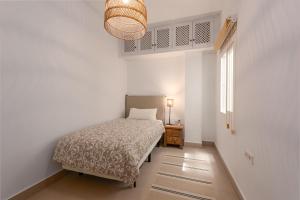 a bedroom with a bed and a lamp and a window at Vivienda Casares in Estepona