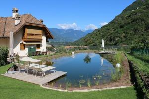 a house with a pond in front of a mountain at Rosengartnerhof Apt Vorberg in Terlano +2 photos
